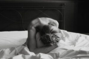 tasteful image of a naked woman from curled over on the bed showing shoulders