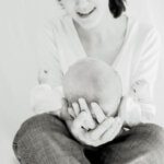 mum holding her newborn in her lap supporting his head