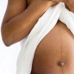 fine art black and white image of a pregnant woman showing bump draped in fabric