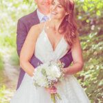 Bride and groom happily cuddling in a summer meadow