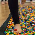 Close up of a person walking barefoot across lego for charity