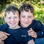 Two young brothers hugging and  happily smiling into camera