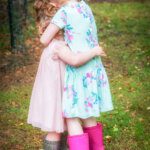 Young sisters hugging in summer dresses