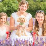Mum, two adult daughters and family poodle smiling in a a lavender field