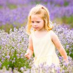 Girl in yellow dress concentrating on flowers in a lavender field