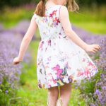 Girl in pretty dress concentrating on flowers in a lavender field
