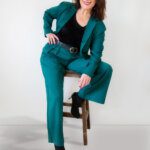 Woman in green trouser suit smiling into camera