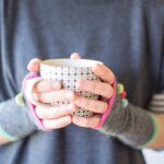 Close up of hands wearing wristwarmers and holding a spotty mug