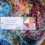 Business card in a pile of colourful offcuts of wool