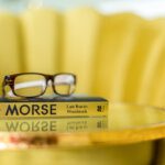 close up of the book woodstock with glasses on top and a yellow chair in the background