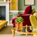 Partial interior of a sitting room fireplace, coffee table and sofa in warm tones of red and yellow