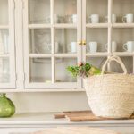 Bright glass fronted kitchen cabinets with a white straw shopping basket