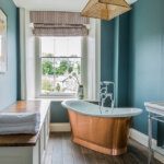 Blue bathroom with a copper roll top bath