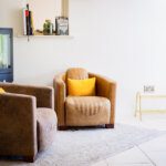 Brightly lit sitting room with modern woodburner and vintage leather chairs