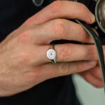 man hands wearing a signet ring holding a vintage camera