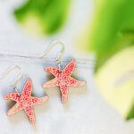 Star fish earrings flatlay through plant