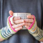 Close up of hands wearing knitted wristwarmers holding  mug