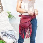 Close up of a model wearing a red fringed hip belt