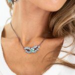 close up of model wearing an intricate black wire designed necklace with blue detail