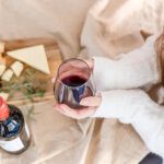 woman viewed from above cupping a red wine glass with cheese and notes