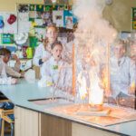 A flash of light explosion in a chemistry lab with surprised students in white coats and goggles