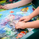Close up of small hands playing in water tray