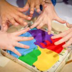 Close up of small hands playing in paint tray from above